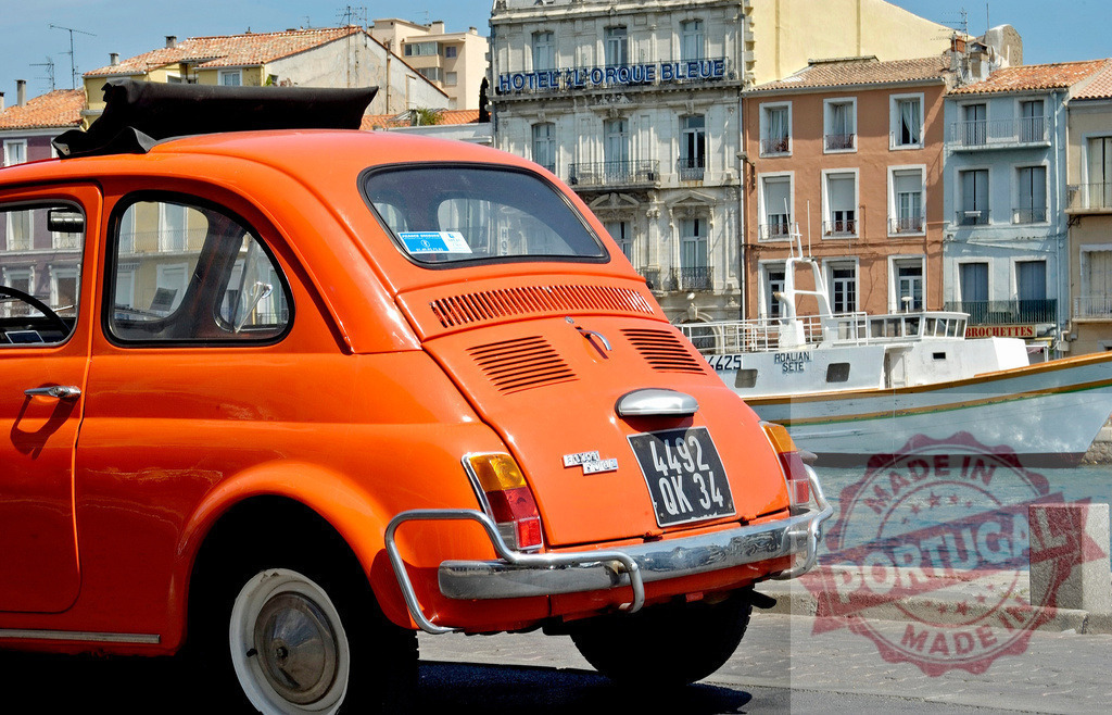 Orange Fiat 500 parked near the Canal du Rhône à Sète in Sète, France | Classic orange Fiat 500 parked in front of the Canal du Rhône à Sète with traditional buildings and boats in the background - Realisiert mit Pictrs.com
