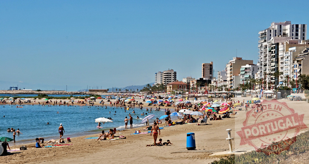 People enjoying summer vacation at a busy city beach | Crowded beach with many people swimming and sunbathing under a clear blue sky - Realized with Pictrs.com