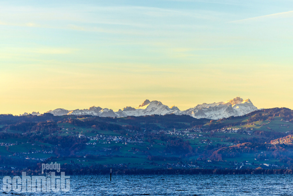 Leuchtender Säntis von Wasserburg am Bodensee | Von Wasserburg am Bodensee eröffnet sich ein eindrucksvoller Blick auf den leuchtenden, schneebedeckten Säntis. Das warme Licht lässt den markanten Gipfel besonders kraftvoll erscheinen und schafft eine faszinierende Verbindung zwischen See, Landschaft und Alpenkulisse. - Realisiert mit Pictrs.com