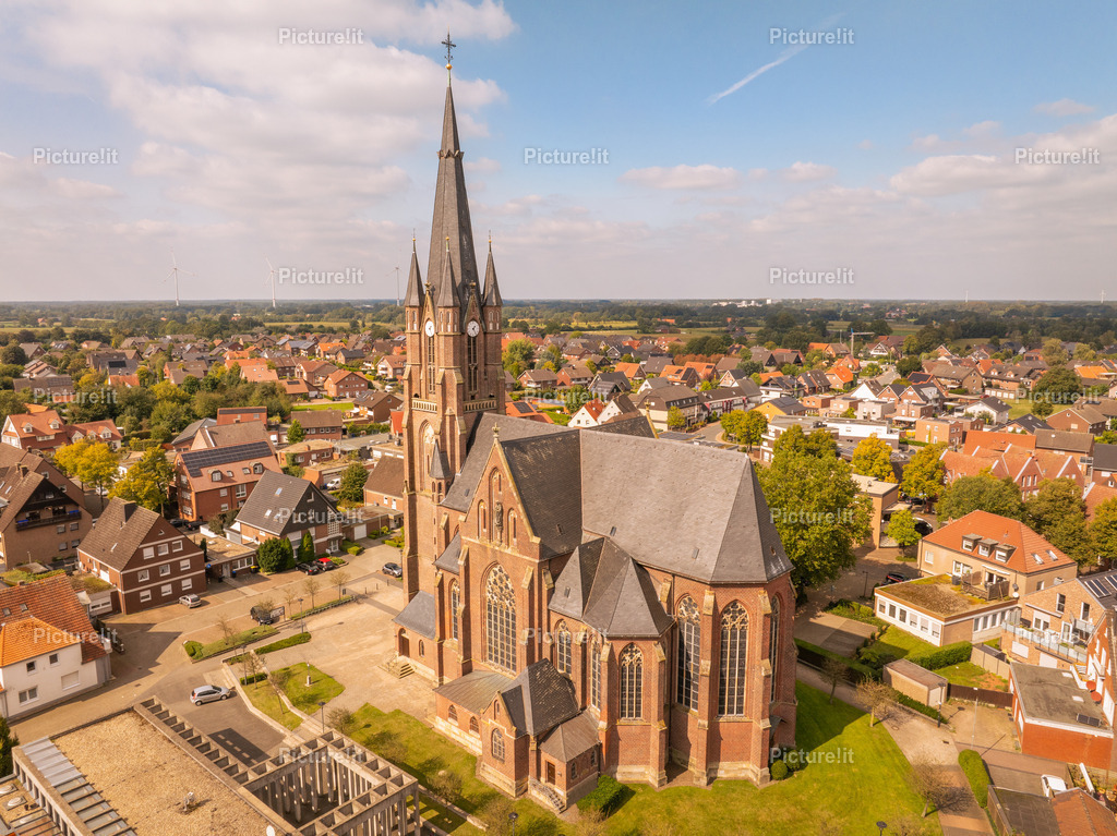 St. Ludgerus Kirche in Weseke | Eine faszinierende Drohnenaufnahme der St. Ludgerus Kirche in Weseke, die die majestätische Architektur und die idyllische Umgebung dieses historischen Wahrzeichens hervorhebt. Die Luftaufnahme zeigt die eindrucksvollen Details der gotischen Bauweise sowie den harmonischen Einklang der Kirche mit dem umliegenden Dorf. Ein spirituelles und kulturelles Zentrum inmitten von Wesekes ländlicher Schönheit, das Besucher und Geschichtsinteressierte gleichermaßen begeistert. - Realisiert mit Pictrs.com