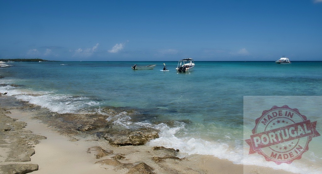 Tropical beach with boats on turquoise ocean water | Tropical beach activity with boats floating on clear blue Caribbean sea water under a sunny sky - Realized with Pictrs.com