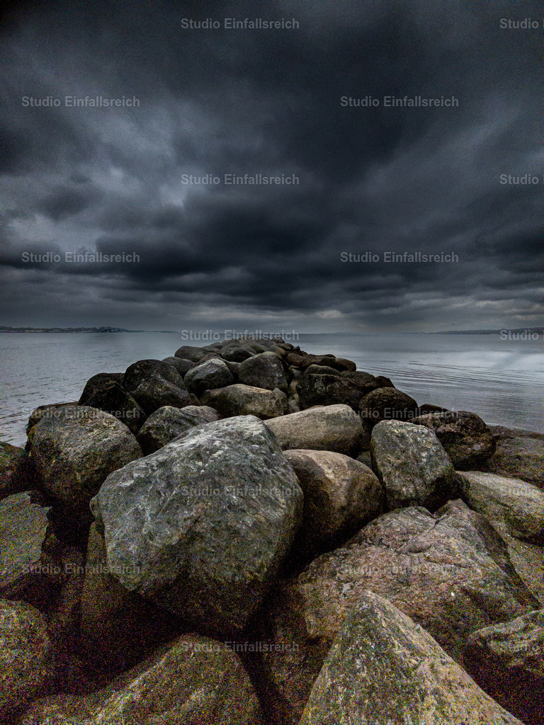 Sturmstimmung – Steinmole an der Ostsee | Eine Steinmole führt ins ruhige Wasser, während sich am Himmel dunkle Gewitterwolken türmen. Dramatik und Weite treffen auf die raue Schönheit der Ostseeküste. Ein kraftvolles Landschaftsmotiv mit Stimmung. Als Fine-Art-Print und Wandbild in verschiedenen Größen erhältlich. - Realisiert mit Pictrs.com