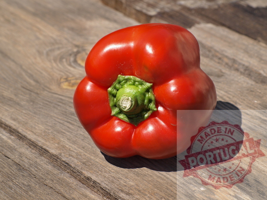Red bell pepper lying on rustic wooden table | Fresh red bell pepper sitting on a textured wooden surface under natural sunlight - Realized with Pictrs.com