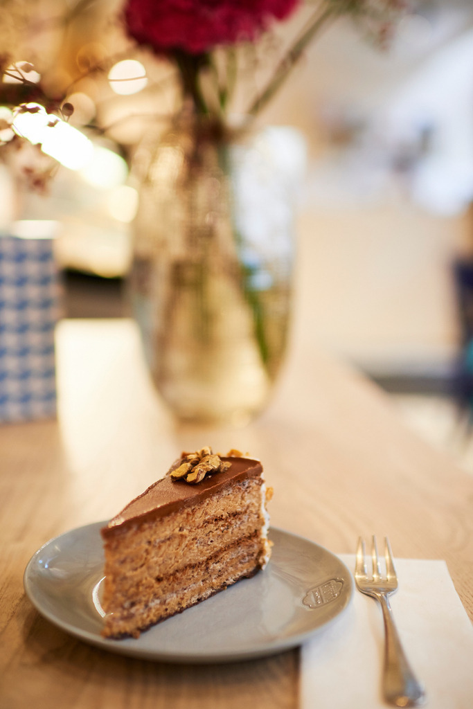 Gregors Konditorei | Wien, Austria - October 20, 2017: Gregors Konditorei, eine Japonaistorte steht auf dem Tisch, im Hintergrund eine Blumenvase und eine Verpackung. - Realisiert mit Pictrs.com