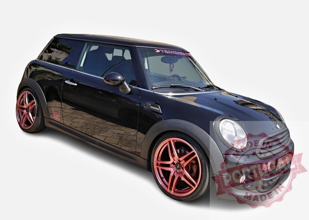 Customized black Mini Cooper with pink alloy wheels parked on a sunny day | Stylish customized black Mini Cooper showcasing pink alloy wheels, parked on a sunny day - Realisiert mit Pictrs.com