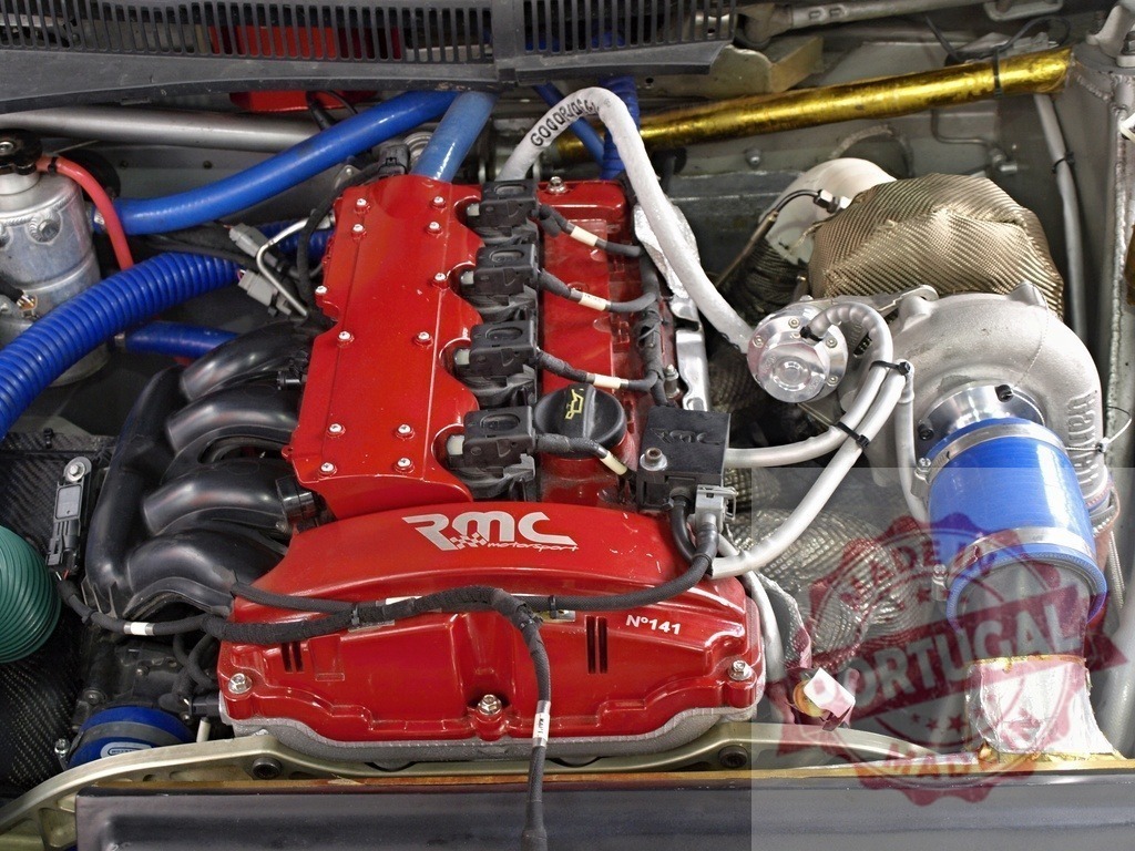 RMC Motorsport rally car engine with turbocharger | Rally car engine bay with red block, blue hoses, and a turbocharger system - Realisiert mit Pictrs.com