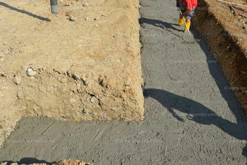 Beton Streifenfundament | Beton zwischen Erdwänden in Fundamentgraben, Arbeiter bei Abziehen des Betons
