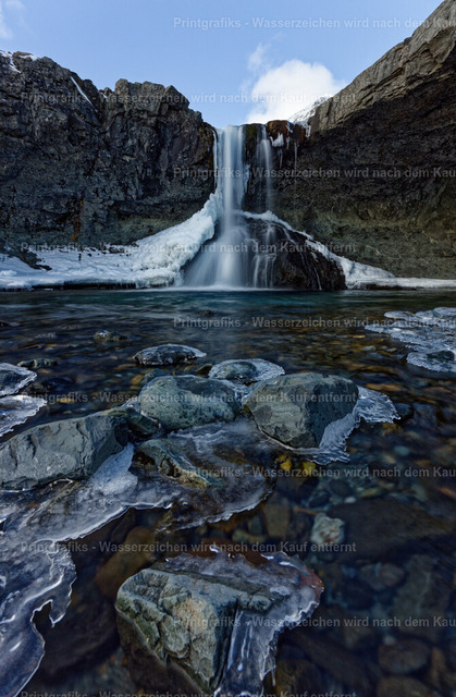 Winterlicher Wasserfall in Island | Ein Wasserfall stürzt zwischen dunklen Felswänden in ein klares Becken, umgeben von Eis und winterlicher Kälte. Die weiche Bewegung des Wassers, die vereisten Steine und die raue Felslandschaft erzeugen eine stille, kraftvolle Naturstimmung. - Realisiert mit Pictrs.com