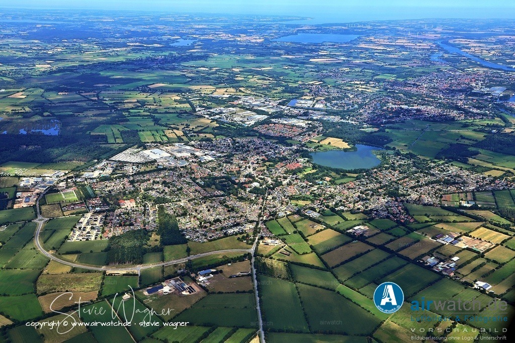 Luftbild Fockbek -  Geografisch liegt Fockbek im Süden des Naturraums Schleswiger Vorgeest | Geografisch liegt Fockbek im Süden des Naturraums Schleswiger Vorgeest und erstreckt sich nördlich des Laufes der Untereider. Das Gemeindegebiet umfasst den fischförmigen Fockbeker See (auch Armensee), das Fockbeker Moor – ein Naturschutzgebiet mit alten Dämmen und reizvoller Landschaft – sowie verschiedene Wohnplätze wie Barris, Ernsttal, Fockbekfeld, Knüll, Langenbrook und Teile von Ahrenstedt. Die Gemeinde ist zentral an die Bundesstraßen 202 und 203 angebunden und liegt damit in unmittelbarer Nähe zu Rendsburg, das etwa 3 Meilen entfernt ist.