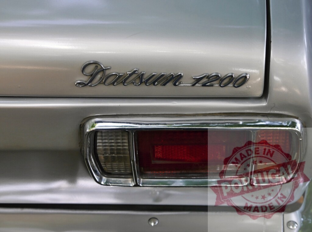 Datsun 1200 badge and taillight on classic silver car | Datsun 1200 car displaying badge and red taillight detail - Realisiert mit Pictrs.com