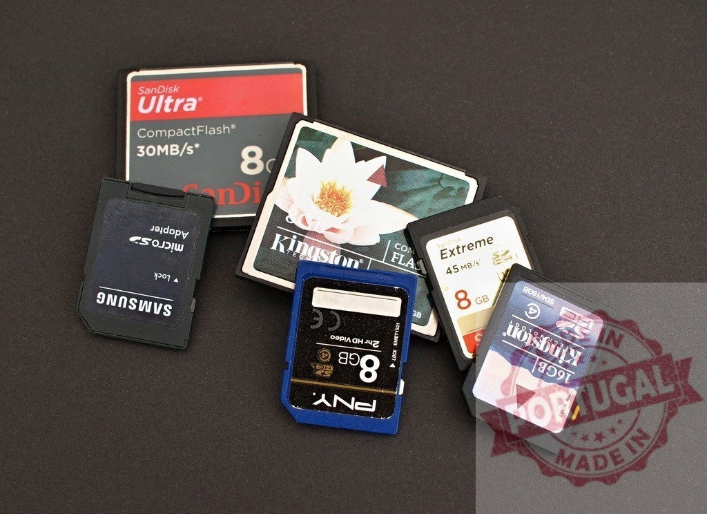 Various digital memory cards and adapters on black background | Grouping different memory cards, including SD, CompactFlash, and microSD with adapters for data storage - Realized with Pictrs.com