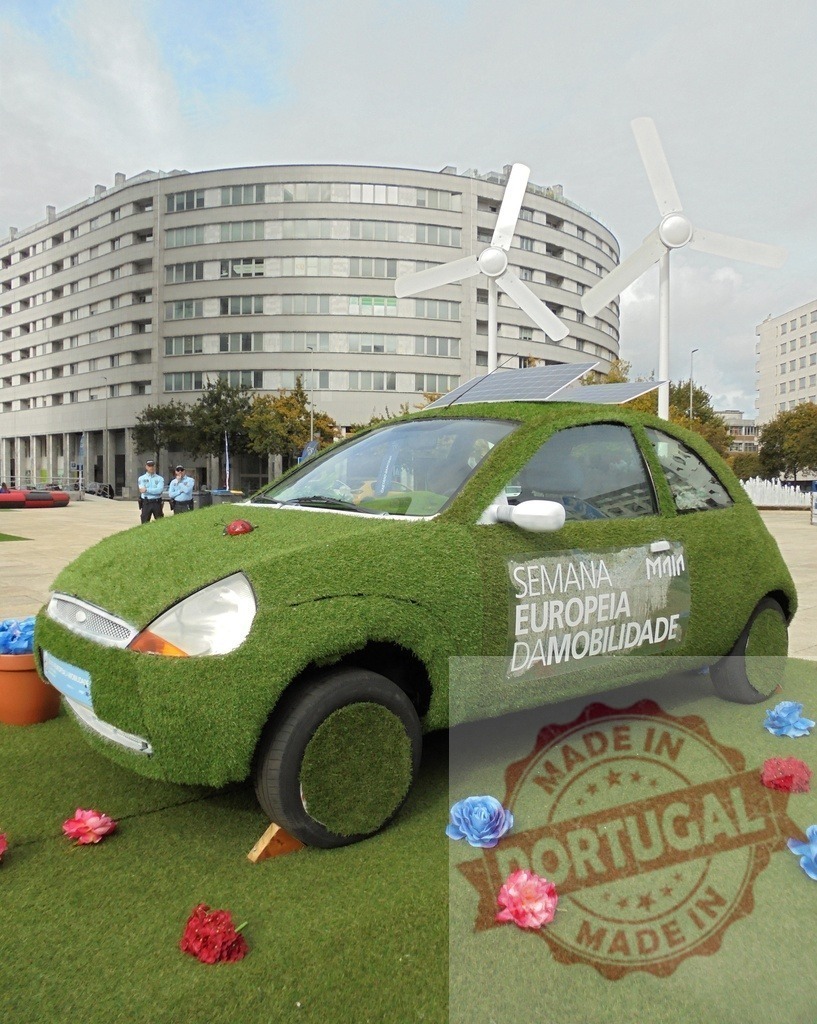 Green car transforming into grass with solar panel and wind turbines | Green car covered with grass and solar panels promoting sustainable mobility - Realized with Pictrs.com