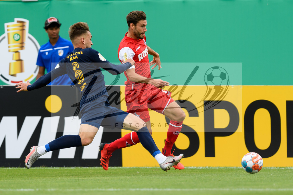 JENKOE20210808_195 | Fussball, Herren: Dennis Slamar (FC Carl Zeiss Jena) und Jonas Hector (1. FC Koeln) im Zweikampf beim Spiel der 1. Runde im DFB-Pokal zwischen FC Carl Zeiss Jena und 1. FC Koeln im Ernst-Abbe-Sportfeld am 08.08.2021 in Jena, Deutschland.DFB / DFL REGULATIONS PROHIBIT ANY USE OF PHOTOGRAPHS AS IMAGE SEQUENCES AND/OR QUASI-VIDEO. - Realisiert mit Pictrs.com