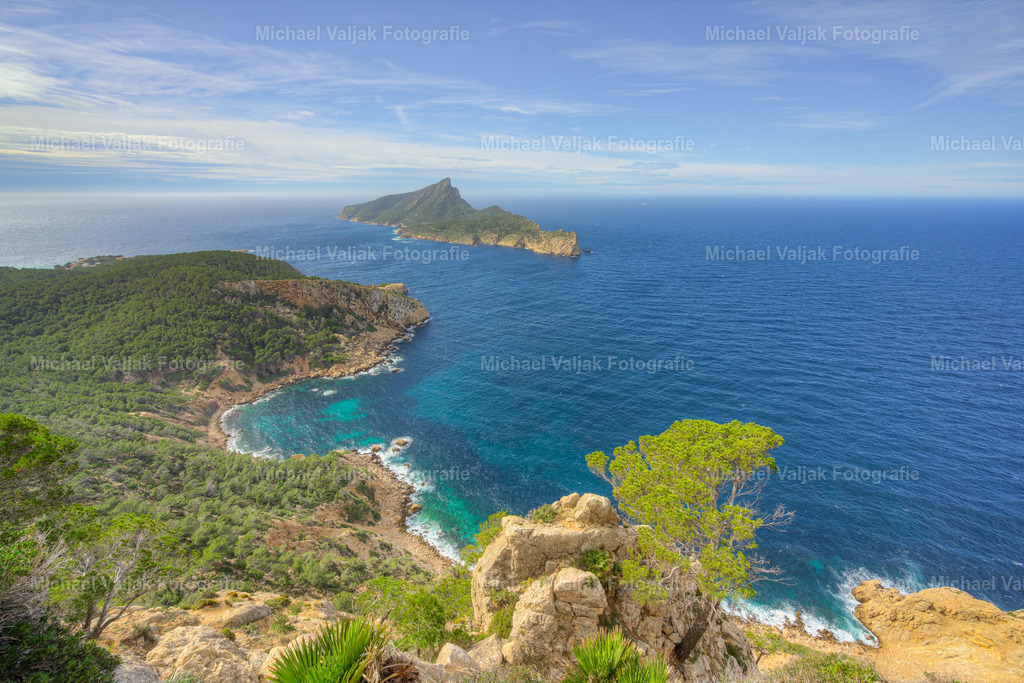 Mirador de la Trapa auf Mallorca | Der Blick vom Mirador de la Trapa hinüber nach Sa Dragonera zeigt an einem sonnigen Tag eine der eindrucksvollsten Landschaftskombinationen Mallorcas. Die klare Luft lässt die Farben besonders intensiv wirken: das tiefe Blau des Meeres, die warmen Erdtöne der Felsen und das satte Grün der Vegetation entlang der Hänge. Sa Dragonera liegt markant vor der Küste, klar abgezeichnet und von Licht durchzogen, das die Form der Insel deutlich hervorhebt. Die Weite der Aussicht, die Struktur der Berge und das leuchtende Mittelmeer verbinden sich zu einer Szene, die gleichzeitig kraftvoll und ruhig wirkt – ein Moment, der die Vielfalt und Schönheit der Westküste in ihrer reinsten Form zeigt. - Realisiert mit Pictrs.com