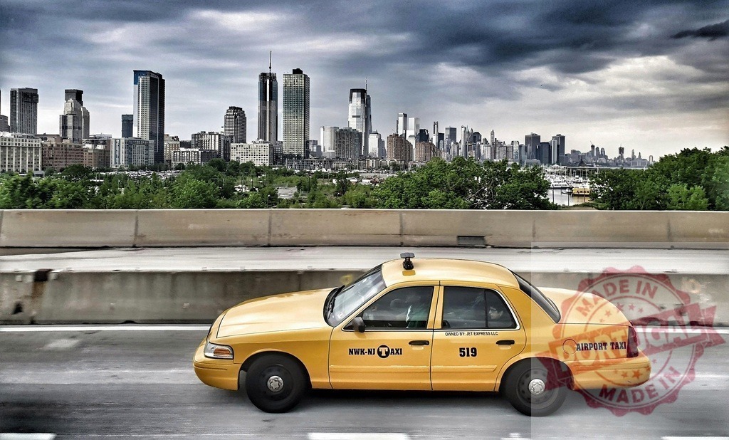 Yellow cab driving on highway with Newark skyline | Yellow airport taxi driving along a highway with the Newark, New Jersey cityscape in the background - Realisiert mit Pictrs.com