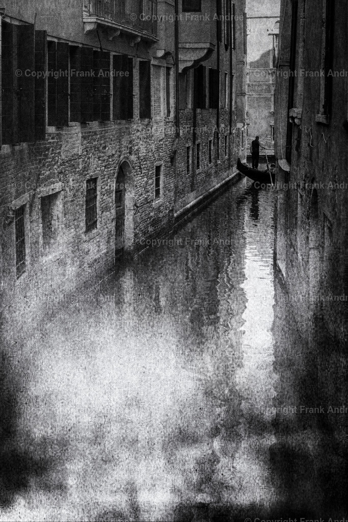 Gondoliere Venedig | In der traumhaften Altstadt von Venedig fährt ein Gondoliere mit seiner Gondel am Ende eines der zahlreichen engen Kanäle. Straßenfotografie aus Italien in schwarz und weiß. - Realisiert mit Pictrs.com