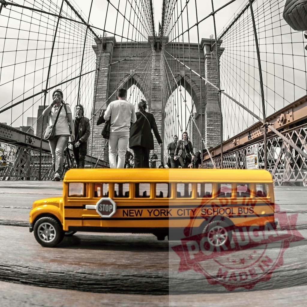 Yellow school bus toy on Brooklyn Bridge with blurred people walking | Miniature New York City school bus on wooden surface with blurred pedestrians walking on Brooklyn Bridge - Realized with Pictrs.com