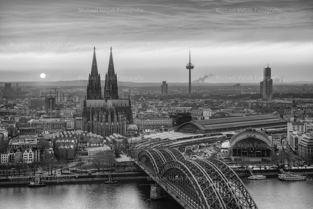 Köln schwarz-weiß | Blick über Köln bei einem intensiven Sonnenuntergang, in einer Schwarz-Weiß-Version. Kurz bevor sie untergeht schafft sie es nochmal durch die Wolken. - Realisiert mit Pictrs.com