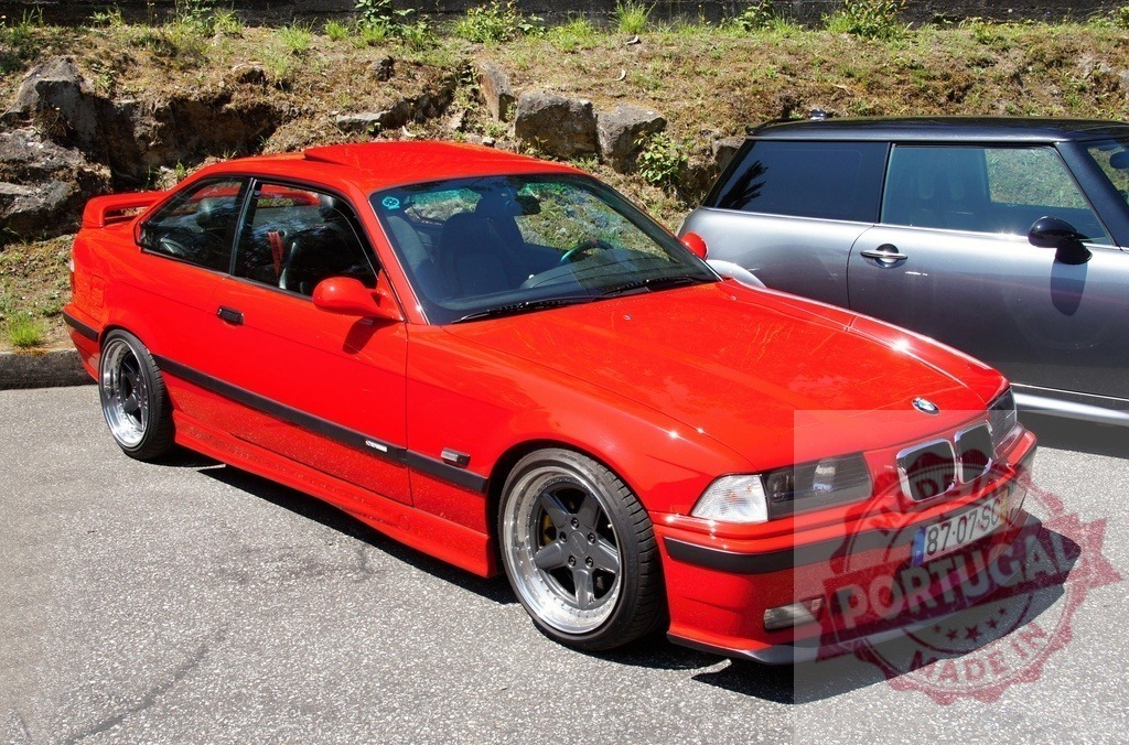 Shiny red BMW M3 E36 parked near a Mini Cooper | Customized and lowered BMW M3 E36 with aftermarket rims and sunroof parked outdoors - Realized with Pictrs.com