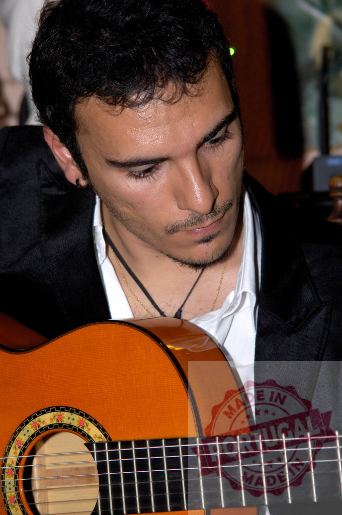 Musician man playing acoustic Spanish guitar intently | Man focusing on playing an acoustic guitar during a musical performance - Realisiert mit Pictrs.com