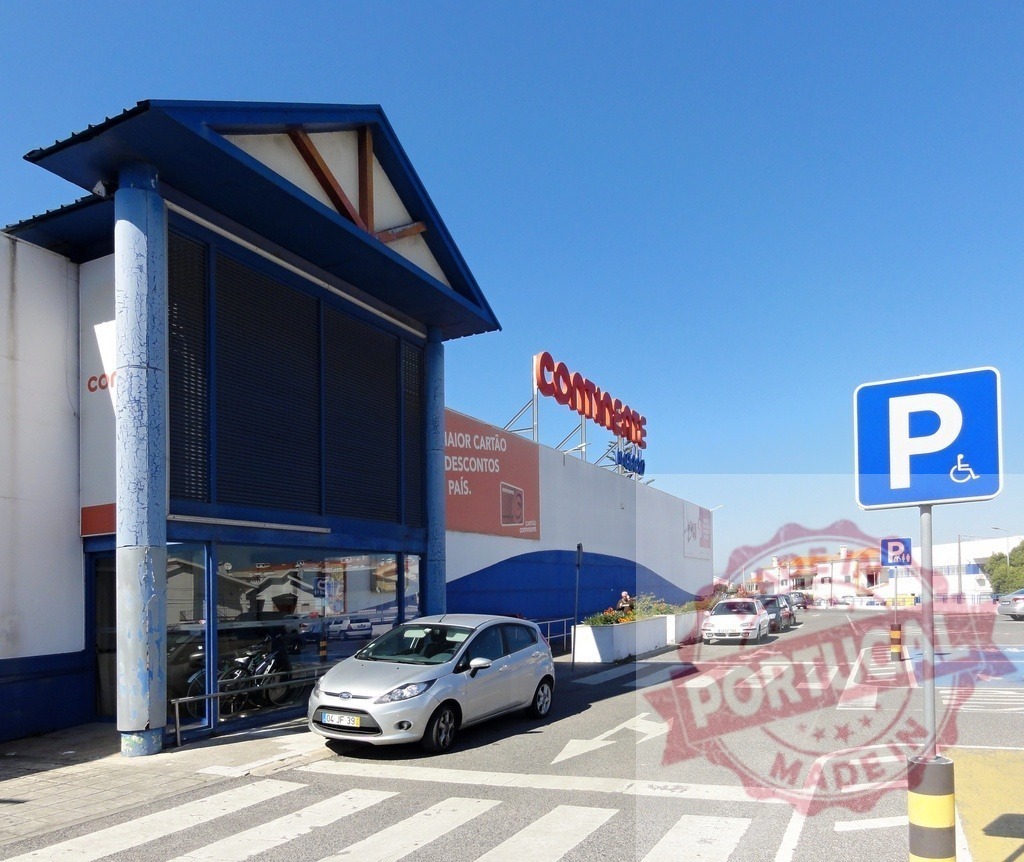 Continente supermarket exterior entrance with disabled parking sign | Continente supermarket building and parking lot under clear blue sky - Realisiert mit Pictrs.com