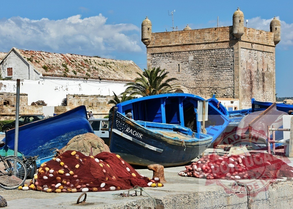 Essaouira port with blue fishing boats and nets | Fishing boats and nets at Essaouira harbor with Skala du Port in the background - Realized with Pictrs.com