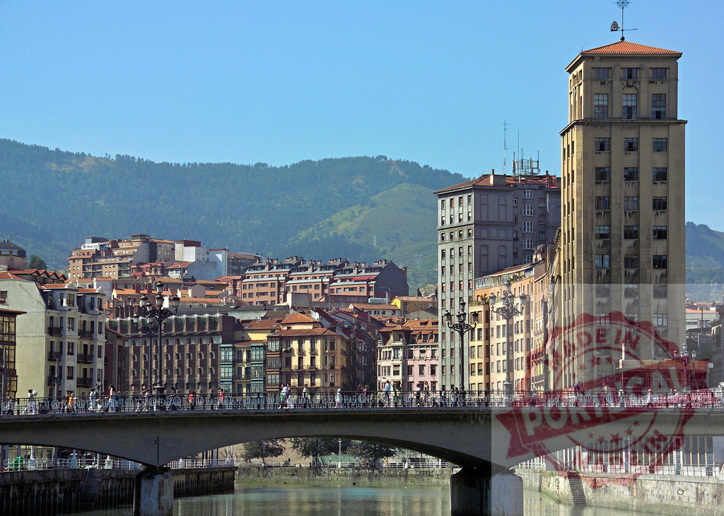Nervión River bridge and city skyline in Bilbao. Spain - Bilbao | People crossing a bridge over the Nervión River with architecture and mountains in Bilbao, Spain - Realized with Pictrs.com