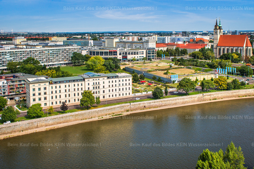 Vitanas-Demenz-Zentrum-Magdeburg-Schleinufer-5569 | Das denkmalgeschützte Gebäude am Schleinufer mit der Elbe im Vordergrund. Heute befindet sich hier das Vitanas Demenz Centrum – doch hinter der heutigen Nutzung verbirgt sich eine wesentlich ältere Geschichte.Das Gebäude entstand um 1850 als Teil des ehemaligen Elbebahnhofs und beherbergte später die Reichsbahndirektion. Nach Zerstörungen im Zweiten Weltkrieg wurde die historische Bausubstanz teilweise wiederhergestellt, umgebaut und erweitert.Auch nach der Deutschen Wiedervereinigung änderte sich die Nutzung mehrfach. 2001/02 wurde das Gebäude zur Akademie der darstellenden Künste umgenutzt. Anschließend erfolgte der Umbau zum heutigen Demenz Centrum, das seitdem ausschließlich Menschen mit Demenz betreut.Aus der Luft wird die besondere Lage unmittelbar an der Elbe besonders deutlich. Im Vordergrund der Fluss, dahinter ein Gebäude, das in seiner Geschichte vom Elbebahnhof über die Reichsbahn bis zur heutigen Pflegeeinrichtung mehrere Kapitel Magdeburger Stadtgeschichte erlebt hat. - Realisiert mit Pictrs.com
