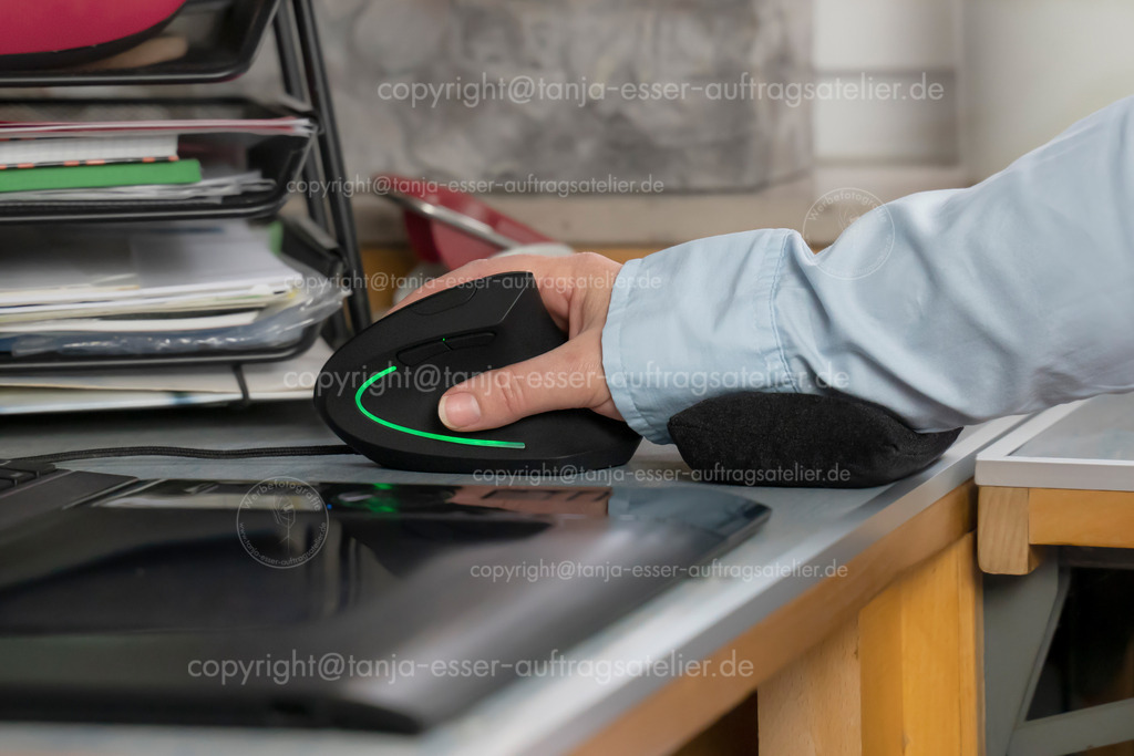 Workstation on the PC with ergonomic mouse | A workplace with a computer. On the desk is a hand in relief position with an ergonomic mouse. In addition to the vertical mouse, a small pillow supports the wrist. Health prevention.