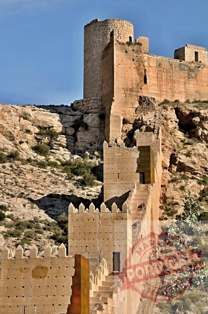 Alcazaba of Almería fortress wall and tower | Ancient Alcazaba of Almería castle walls and towers standing on a hill under blue sky - Realized with Pictrs.com