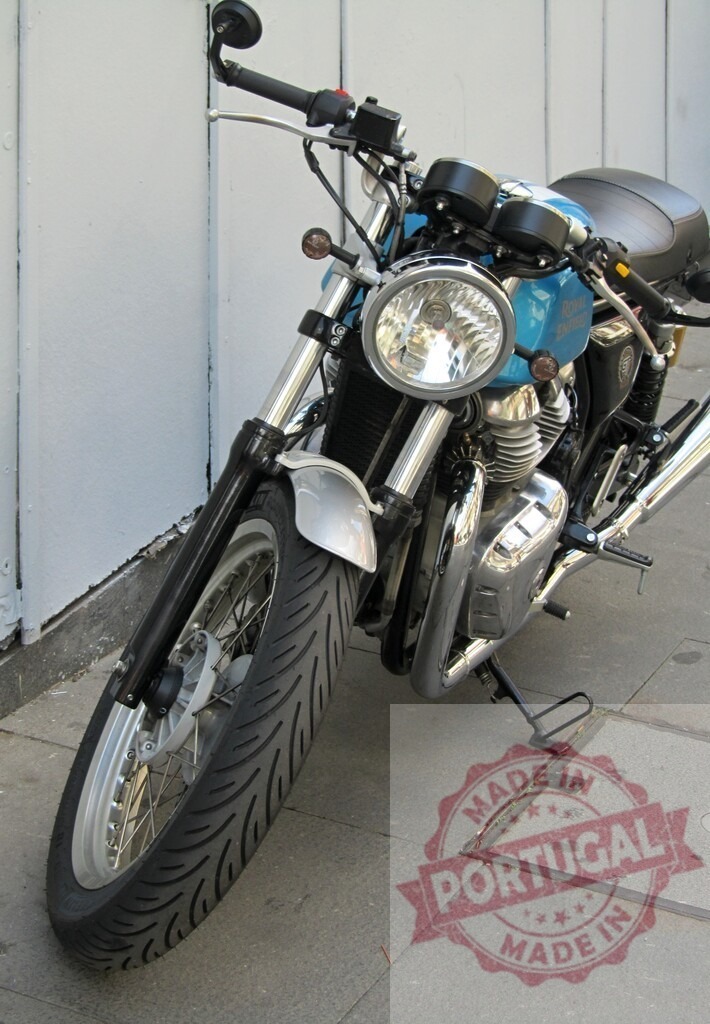 Royal Enfield Continental GT 650 motorcycle parked near a white wall | Front view of a Royal Enfield Continental GT 650 motorcycle parked on a sidewalk - Realized with Pictrs.com