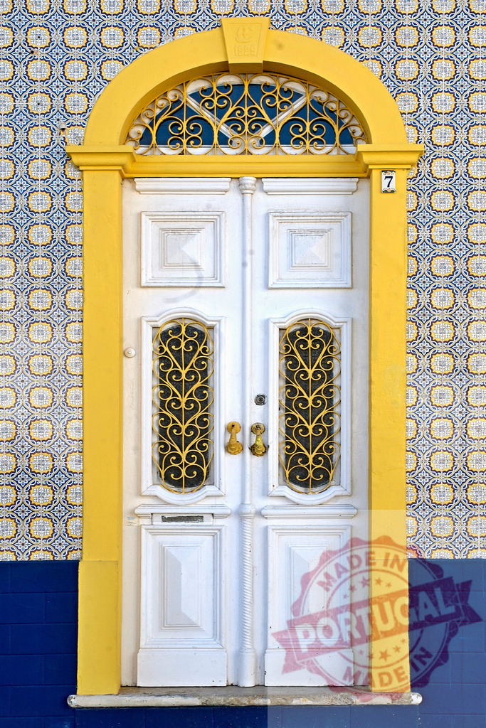 Traditional Portuguese doorway with yellow frame and azulejo tiles | White door featuring ornate ironwork and vibrant azulejo tiles in Portugal - Realisiert mit Pictrs.com
