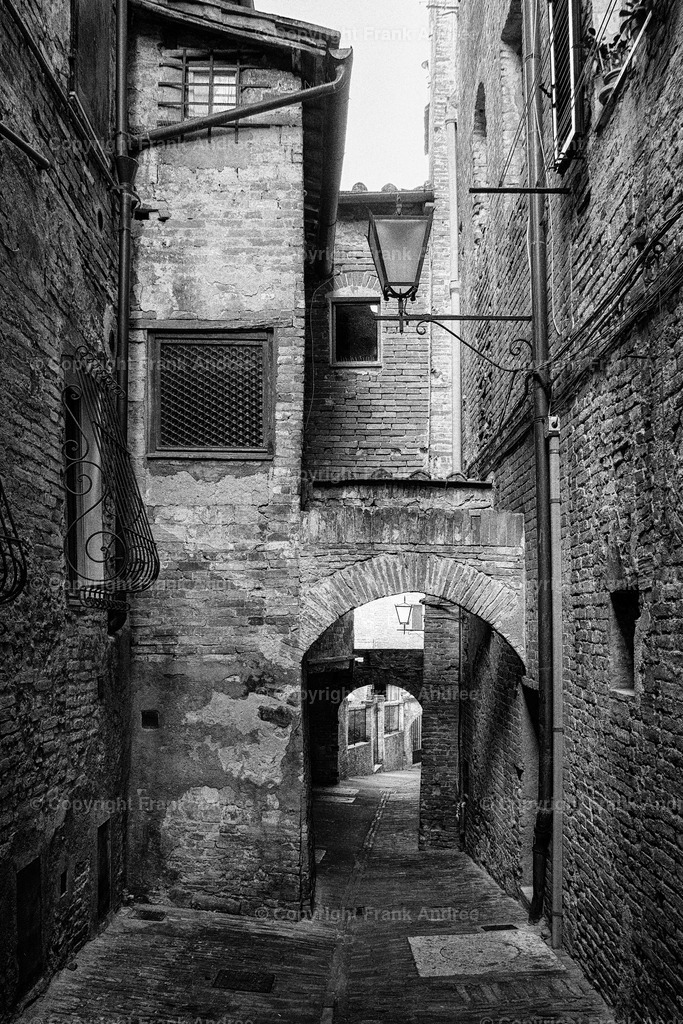 Siena | Blick entlang einer engen Gasse in der bezaubernden Altstadt von Siena. Schwarz weiß Fotografie aus der Toskana. - Realisiert mit Pictrs.com
