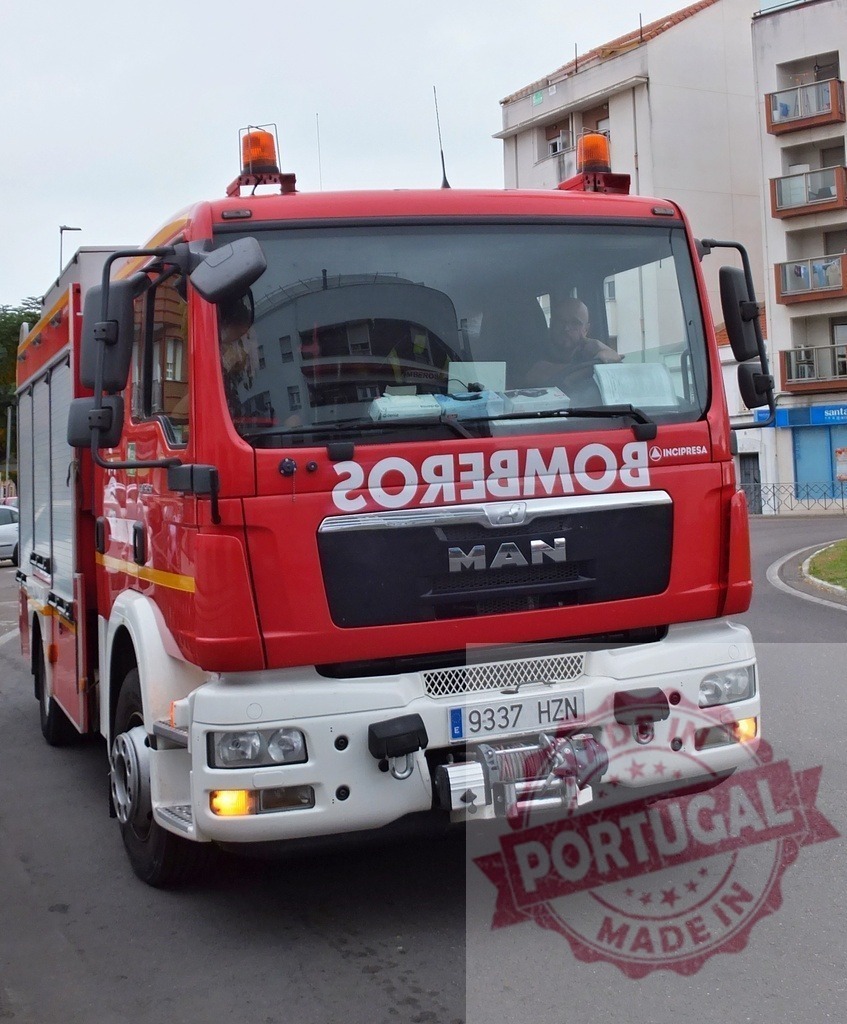 Red MAN bomberos fire truck driving on street | Red bomberos MAN fire truck driving on a city street, ready for emergency service - Realized with Pictrs.com