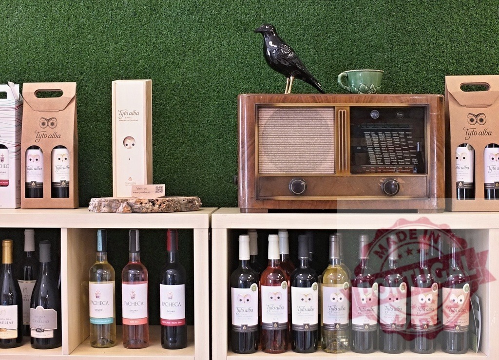 Tyto Alba wine bottles and vintage radio on shelf with grass wall | Wine bottles, a vintage radio, and a bird figurine decorating shelves against a green grass wall - Realized with Pictrs.com