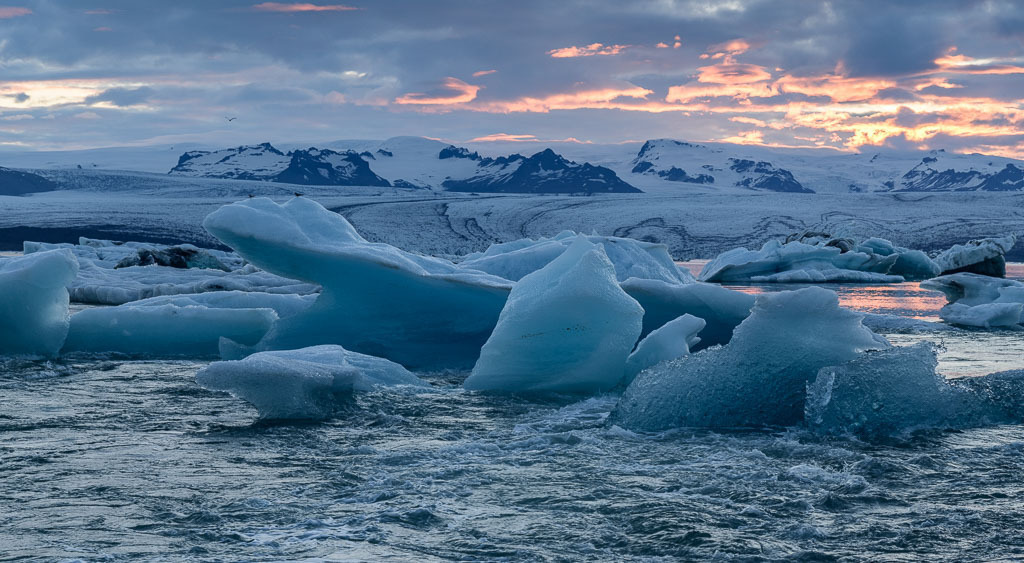 island-2019-311 | Jökulsárlón ist eine Gletscherlagune, die an den Nationalpark Vatnajökull im Südosten Islands angrenzt. Im Wasser schwimmen unzählige Eisberge des Vatnajökull-Gletschers. Die Lagune fließt durch einen kurzen Wasserlauf in den Atlantik. An diesem schmalen Kanal entstand dieses Bild, das die Dynamik der treibenden Eisberge sichtbar macht. - Realisiert mit Pictrs.com
