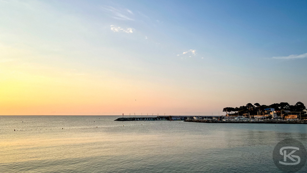 Goldener Sonnenaufgang über dem Hafen von Fréjus, Saint-Raphaël – Côte d’Azur | Stimmungsvolle Panorama-Aufnahme vom Sonnenaufgang in Fréjus, Saint-Raphaël: Das ruhige Mittelmeer spiegelt das erste goldene Licht des Tages wider, mit Blick auf die Hafenmole und die Küstenlinie der Côte d’Azur. - Realisiert mit Pictrs.com