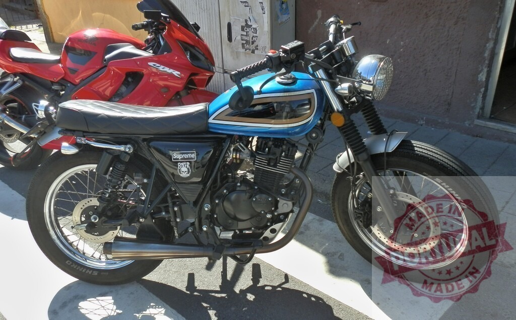 Stylish blue and black motorcycle parked on the street | Modern motorcycle parked near the sidewalk with another red motorcycle in the background - Realized with Pictrs.com