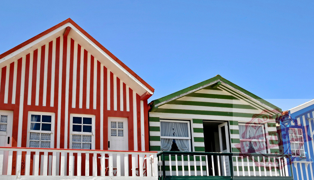 Costa Nova beach houses with colorful striped facades | Costa Nova houses feature vibrant striped facades under a clear blue sky - Realisiert mit Pictrs.com