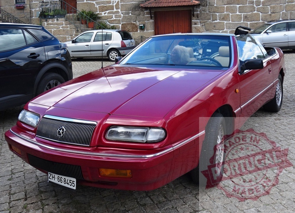 Red Chrysler LeBaron convertible parked on cobblestone street | Red Chrysler LeBaron convertible parked on a cobblestone street in a traditional village setting - Realisiert mit Pictrs.com