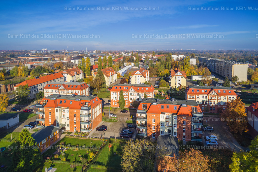 Magdeburg_Salbke_Freundschaftsweg-0007 | Am Freundschaftsweg in Magdeburg-Salbke zeigt sich eine Wohnlage mit viel Grün und einem gewachsenen Wohnumfeld. Die Wohnhäuser mit ihren roten Ziegeldächern, hellen Fassaden und begrünten Innenbereichen bilden ein abwechslungsreiches Bild. Zwischen den Gebäuden liegen kleine Gärten, Bäume und Freiflächen, die dem Viertel einen offenen und wohnlichen Charakter geben. –  – Salbke liegt im Süden Magdeburgs und verbindet städtisches Wohnen mit der Nähe zur Landschaft. Hier geht es vielerorts etwas ruhiger zu als in der Innenstadt. Unterschiedliche Wohnformen, gewachsene Straßen und grüne Zwischenräume prägen den Stadtteil und machen ihn zu einem eigenen Stück Magdeburg. –  – Gerade aus der Vogelperspektive wird sichtbar, wie die Häuser angeordnet sind und wie viel Platz zwischen den Wohngebäuden bleibt. Die Gärten und Bäume bringen Farbe ins Wohngebiet und verändern sein Gesicht mit den Jahreszeiten – vom frischen Grün im Frühjahr bis zu den warmen Herbstfarben. –  – Ein Blick auf den Alltag in Salbke: ein Wohnviertel mit eigenem Charakter, begrünten Außenbereichen und einem Umfeld, in dem Wohnen und Freiraum zusammengehören. - Realisiert mit Pictrs.com