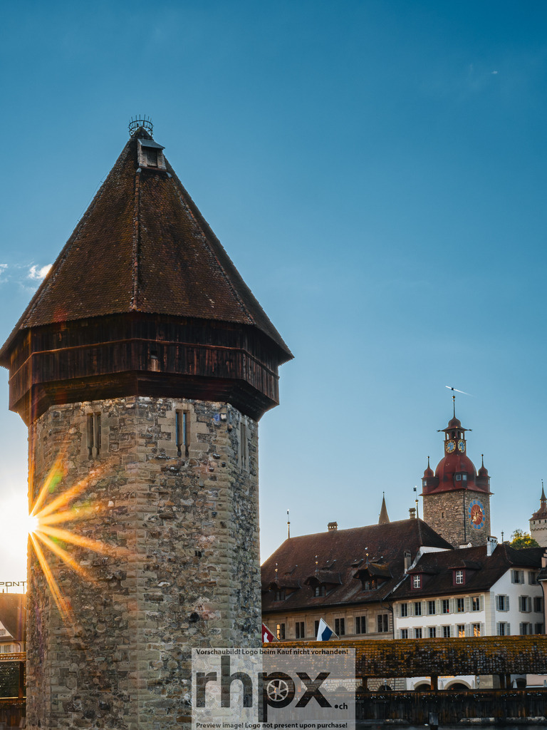 Kapellbrücke und Wasserturm Luzern im Abendlicht | Die tief stehende Sonne bricht sternförmig hinter dem Wasserturm hervor und taucht die Kapellbrücke sowie die Altstadt von Luzern in warmes Abendlicht.  - Realized with Pictrs.com