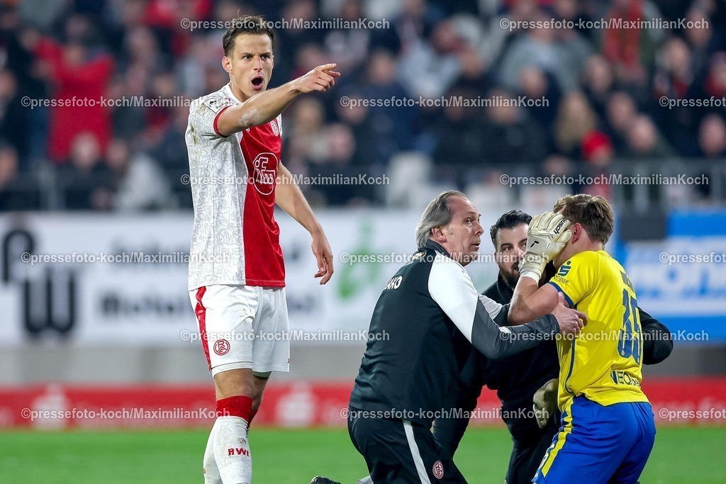 RWE04032601086 | 2026.03.04, Fußball, 3.Liga Herren, Rot-Weiss Essen -  SV Waldhof Mannheim, Stadion Hafenstraße, 27.Spieltag, Saison 2025 / 2026: Torwart Felix Wienand&nbsp;(Rot-Weiss Essen #35) kniet verletzt auf dem Spielfeld nach dem Zünden von Pyrotechnik im Gästeblock der Mannheimer. Ein Lauter Knall durch einen geworfenen Böller verletzt den Torwart und führt zu einer Spielunterbrechung Michael Schultz&nbsp;(Rot-Weiss Essen #04) gestikulierend auf dem Spielfeld   DFB regulations prohibit any use of photographs as image sequences and or quasi-video.
