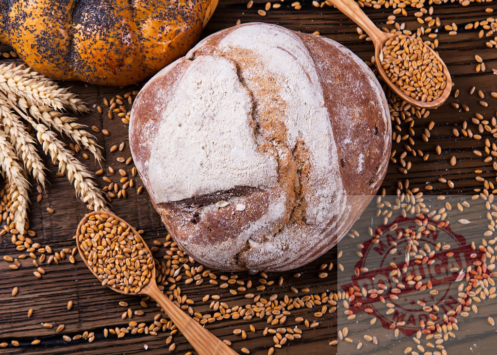 Fresh rustic bread and wheat grains on wooden table | Freshly baked bread loaves with scattered wheat grains and ears on a rustic wooden surface - Realized with Pictrs.com