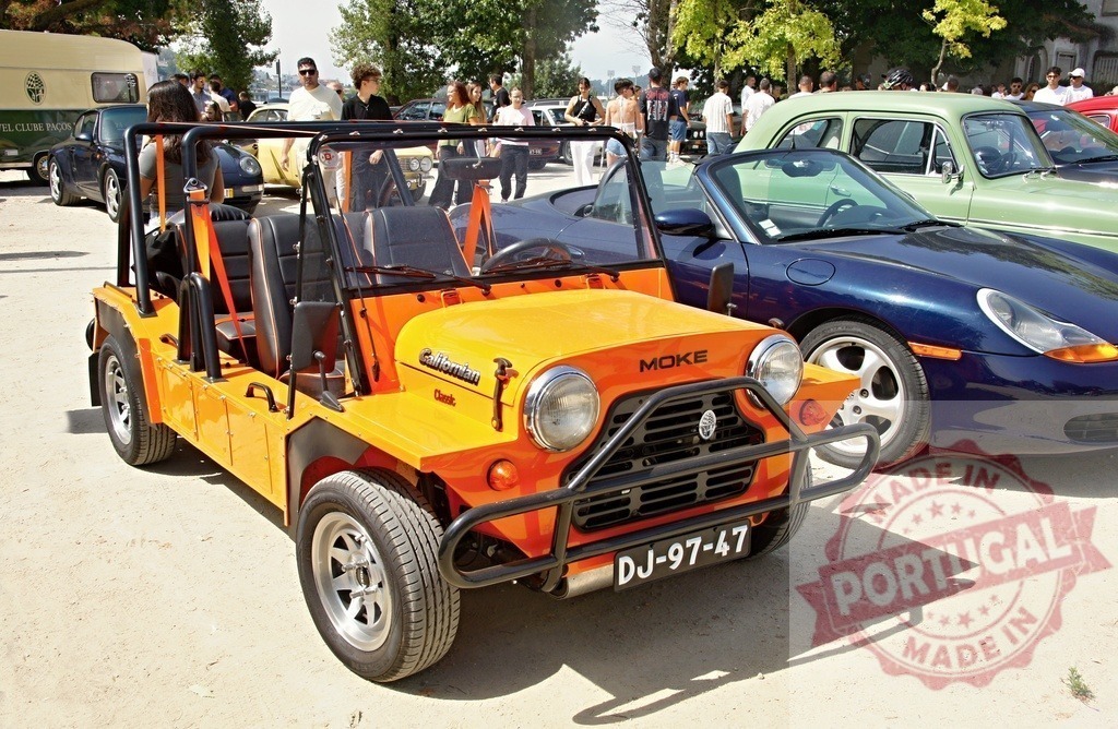 Orange Mini Moke and other classic cars at outdoor show | Orange Mini Moke convertible on display at a classic car show on a sunny day - Realisiert mit Pictrs.com