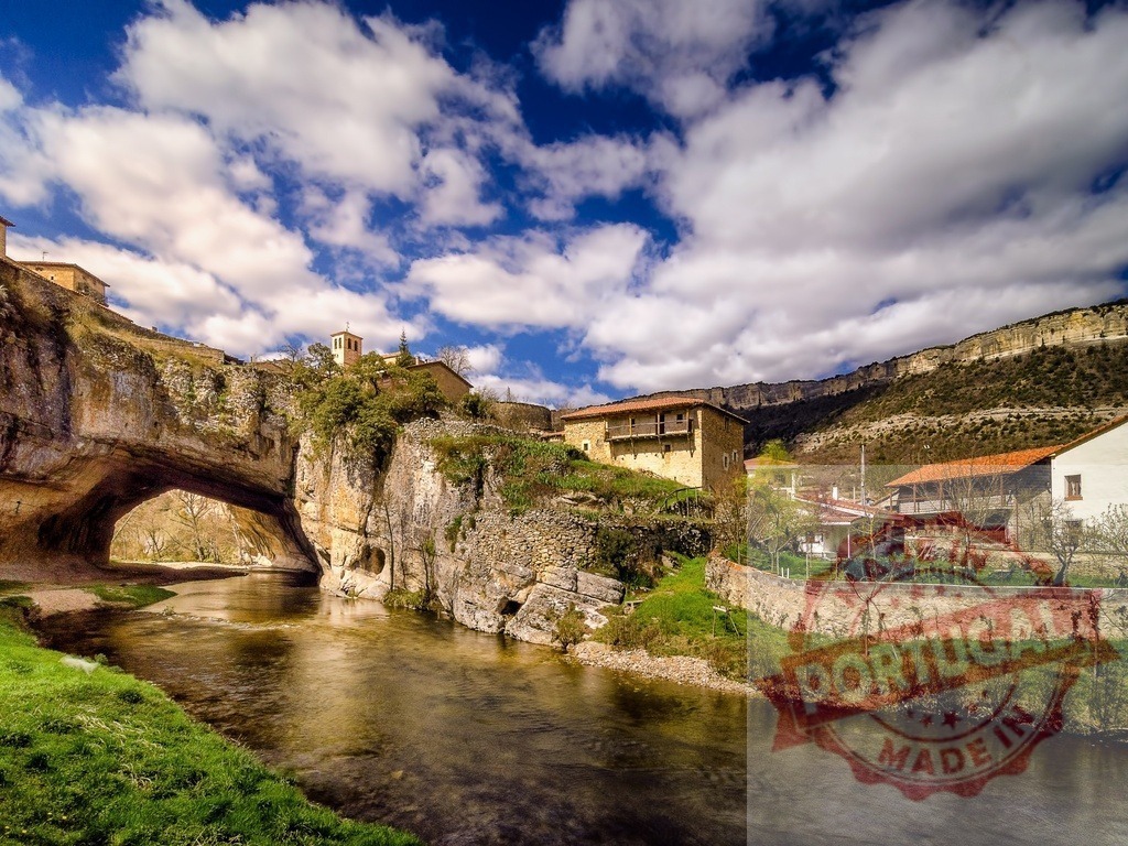 Puentedey village natural rock bridge over Nela river | Puentedey village built atop natural stone arch spanning Nela river, with mountains and cloudy sky - Realized with Pictrs.com