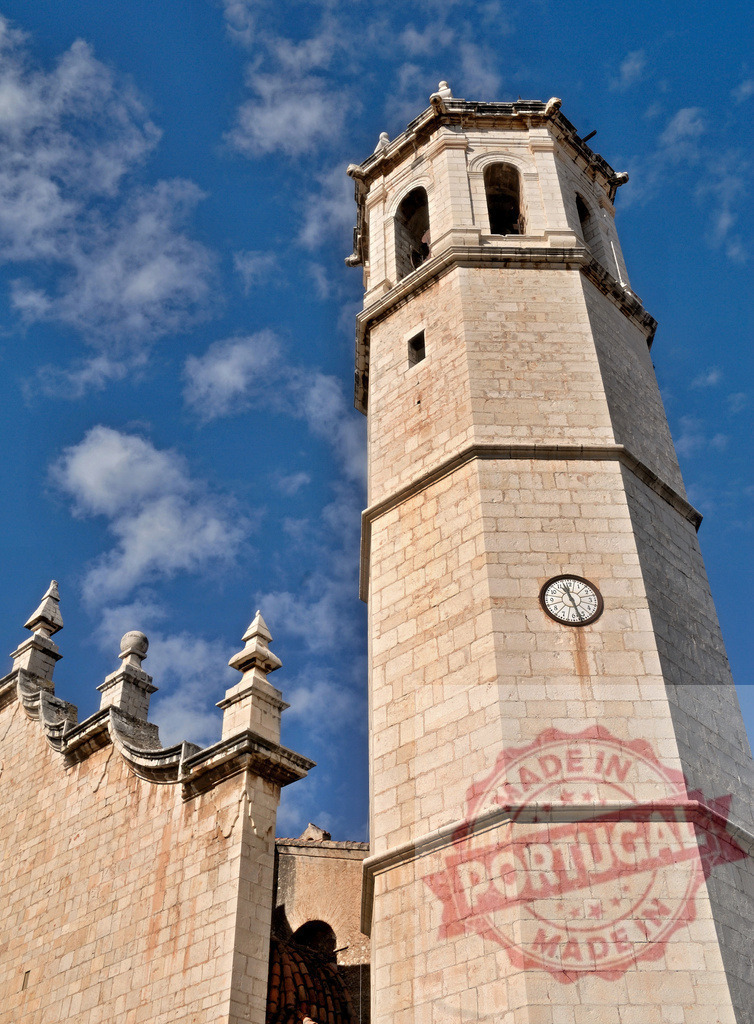 Historic church clock tower with blue sky | Stone church clock tower reaching towards a bright blue sky with white clouds - Realized with Pictrs.com