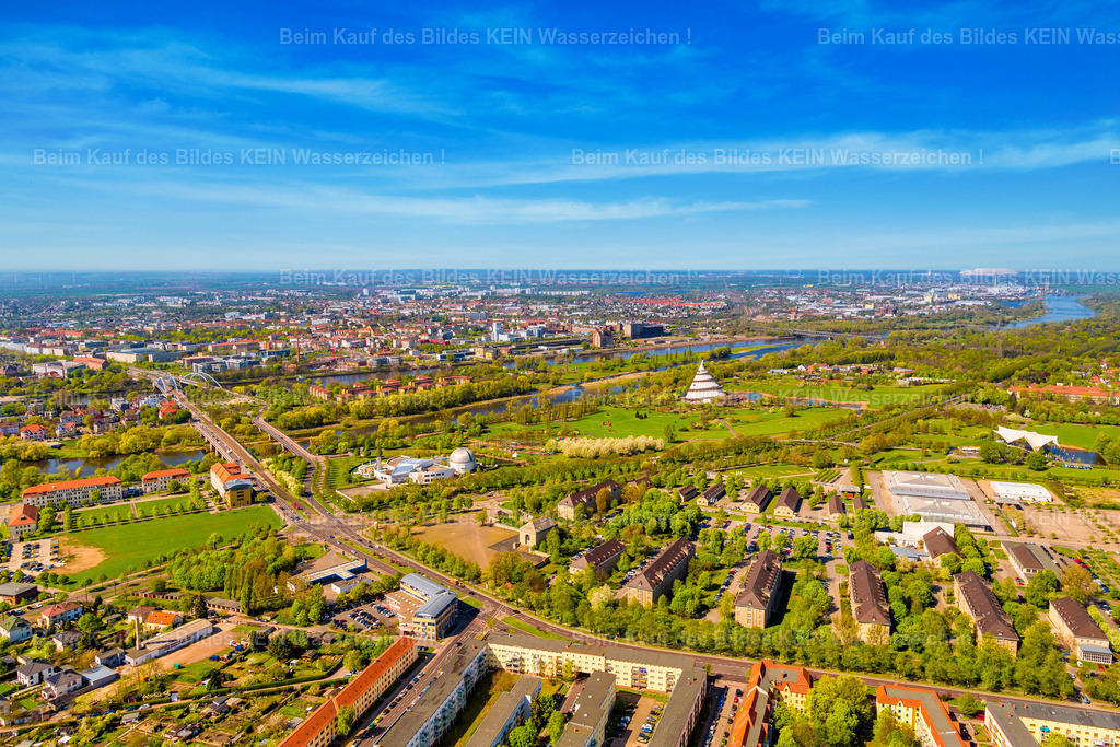 Magdeburg Jerichower Tessenow Elbauenpark -8801 | Diese sommerliche Luftaufnahme aus dem Tragschrauber zeigt die markanten Häuser der Tessenowstraße inmitten einer außergewöhnlich grünen Umgebung. Im Mittelpunkt der Aufnahme liegen der Elbauenpark und das Nemo-Erlebnisbad, die diesen Teil Magdeburgs als beliebtes Freizeit- und Erholungsgebiet prägen. Im Hintergrund verläuft die Elbe quer durch das Bild und bildet die natürliche Grenze zur Magdeburger Innenstadt. Die satten Grüntöne, der klare Sommerhimmel und die weitläufige Parklandschaft verleihen dem Panorama eine besonders freundliche und lebendige Ausstrahlung.Solche großräumigen Stadtansichten zeigen Magdeburg aus einer Perspektive, die nur aus dem Tragschrauber möglich ist. Für Ihren individuellen Luftbildkalender können Sie gezielt Stadtteile, Wohngebiete oder besondere Orte auswählen, die für Ihr Unternehmen oder Ihre persönliche Geschichte eine besondere Bedeutung haben. Aus einem Luftbildarchiv mit über 1.000 Aufnahmen entsteht so ein Kalender, der exakt auf Ihre Wünsche abgestimmt ist.Sie entscheiden selbst, welche Motive Ihren Kalender schmücken sollen – ich kümmere mich um die professionelle Gestaltung und Umsetzung. Die individuelle Motivauswahl gehört selbstverständlich zum Service und ist ohne zusätzliche Kosten möglich. So erhalten Sie einen hochwertigen Luftbildkalender, der Magdeburg genau so zeigt, wie Sie die Stadt präsentieren möchten. - Realisiert mit Pictrs.com