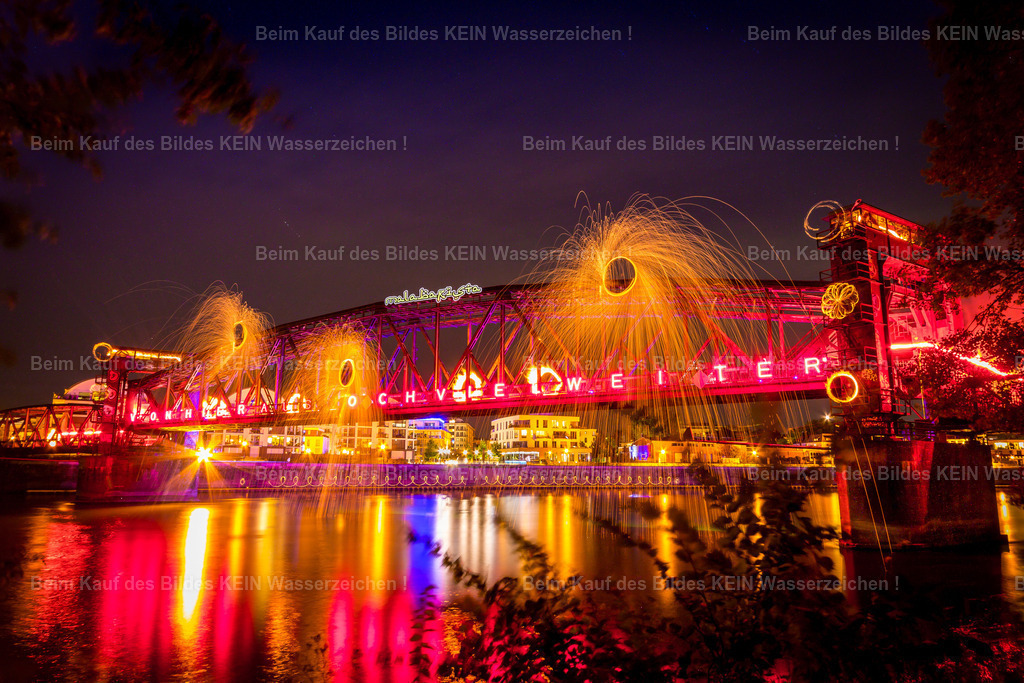 Lichtkunst_Daniel_Hubbrücke_3520-3 | Diese außergewöhnliche Nachtaufnahme zeigt die historische Hubbrücke während einer spektakulären Licht- und Feuerinszenierung. Die imposante Stahlkonstruktion wird von 18 Feuerkünstlern eindrucksvoll in Szene gesetzt und verwandelt sich für einen kurzen Moment in eine faszinierende Kulisse aus Licht, Funken und leuchtenden Farben. Die aufwendig inszenierte Aufnahme verbindet kreative Lichtkunst mit einem der bekanntesten technischen Denkmäler Magdeburgs und zählt zu den außergewöhnlichsten Motiven des Magdeburger Luftbildkalenders.Dieses Motiv zeigt, wie vielfältig die Brücken Magdeburgs in Szene gesetzt werden können. Neben klassischen Tagesaufnahmen stehen auch außergewöhnliche Nachtmotive, besondere Lichtstimmungen und spektakuläre Inszenierungen zur Auswahl. Die gezeigten Luftaufnahmen dienen als Inspiration und können jederzeit durch andere Brückenmotive aus dem umfangreichen Luftbildarchiv ersetzt oder ergänzt werden.So entsteht ein individueller Firmenkalender mit persönlichem und regionalem Bezug. Sie wählen Ihre Lieblingsmotive aus, ich übernehme die professionelle Gestaltung und Umsetzung. Die individuelle Motivauswahl gehört selbstverständlich zum Service und ermöglicht einen Brückenkalender, der die schönsten und außergewöhnlichsten Brücken Magdeburgs genau nach Ihren Vorstellungen präsentiert – ohne zusätzliche Kosten. - Realisiert mit Pictrs.com