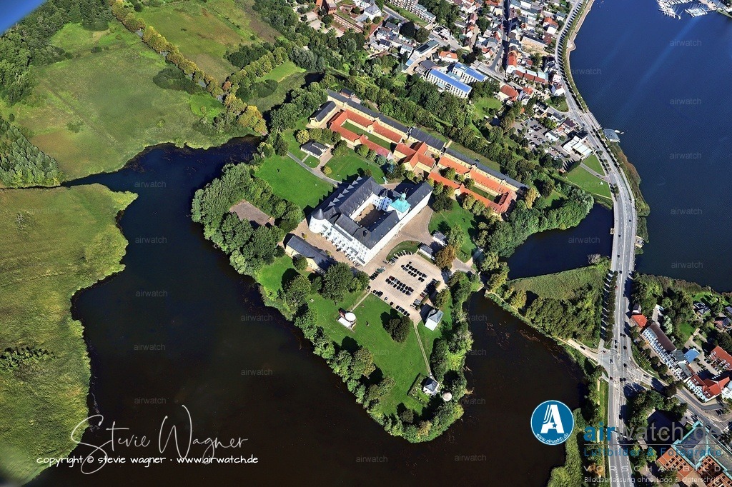 Luftbilder Ostseefjord Schlei, Schloss Gottorf, Anflug Westen | Schloss Gottorf in Schleswig: Das Archäologische Landesmuseum Schleswig, auch bekannt als Museum für Archäologie Schloss Gottorf, befindet sich auf der Schlossinsel in Schleswig und zählt zu den bedeutendsten Museen seiner Art in Nordeuropa. Es ist Teil der Stiftung Schleswig-Holsteinische Landesmuseen Schloss Gottorf, die seit 1999 beide Häuser unter einem Dach vereint. Das Museum besitzt mehr als 10 Millionen Funde aus 80.000 Jahren Menschheitsgeschichte, wobei der größte Teil aus Ausgrabungen in Schleswig-Holstein stammt.